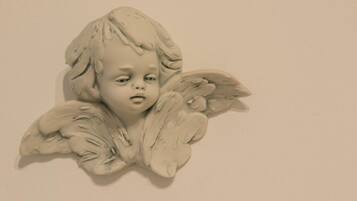Escultura de um anjo com asas, fixada na parede.