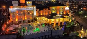 A multi-story hotel with a large outdoor pool area, multiple balconies, and a well-lit facade. - Club House Hotel (Villa Carlos Paz)