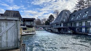 A river with a wooden dock and buildings on the opposite bank. - Betsie Riverside Resort (Benzonia)