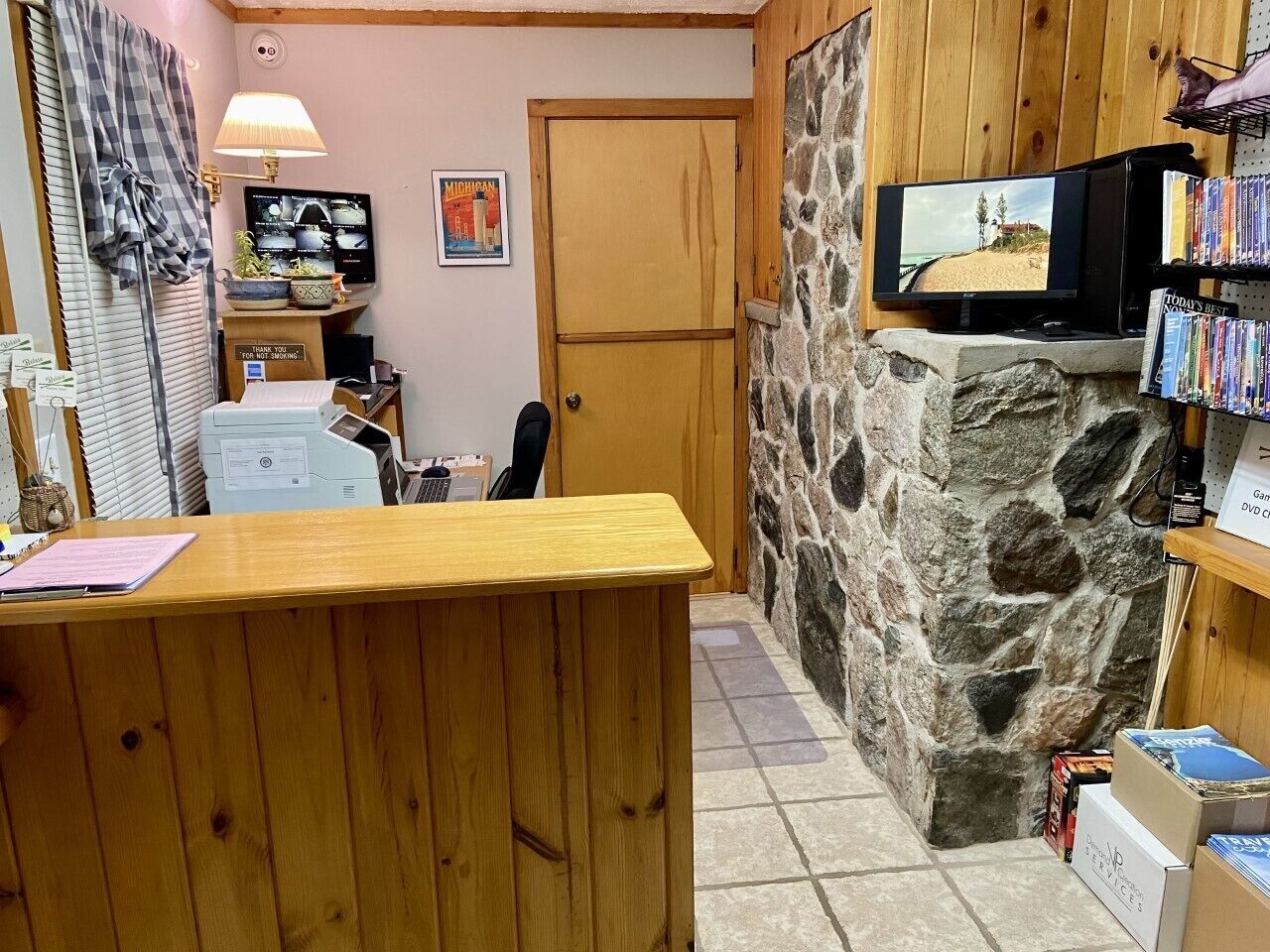 Una zona de recepción con un escritorio de madera, una pared de piedra, un televisor y un reproductor de DVD.