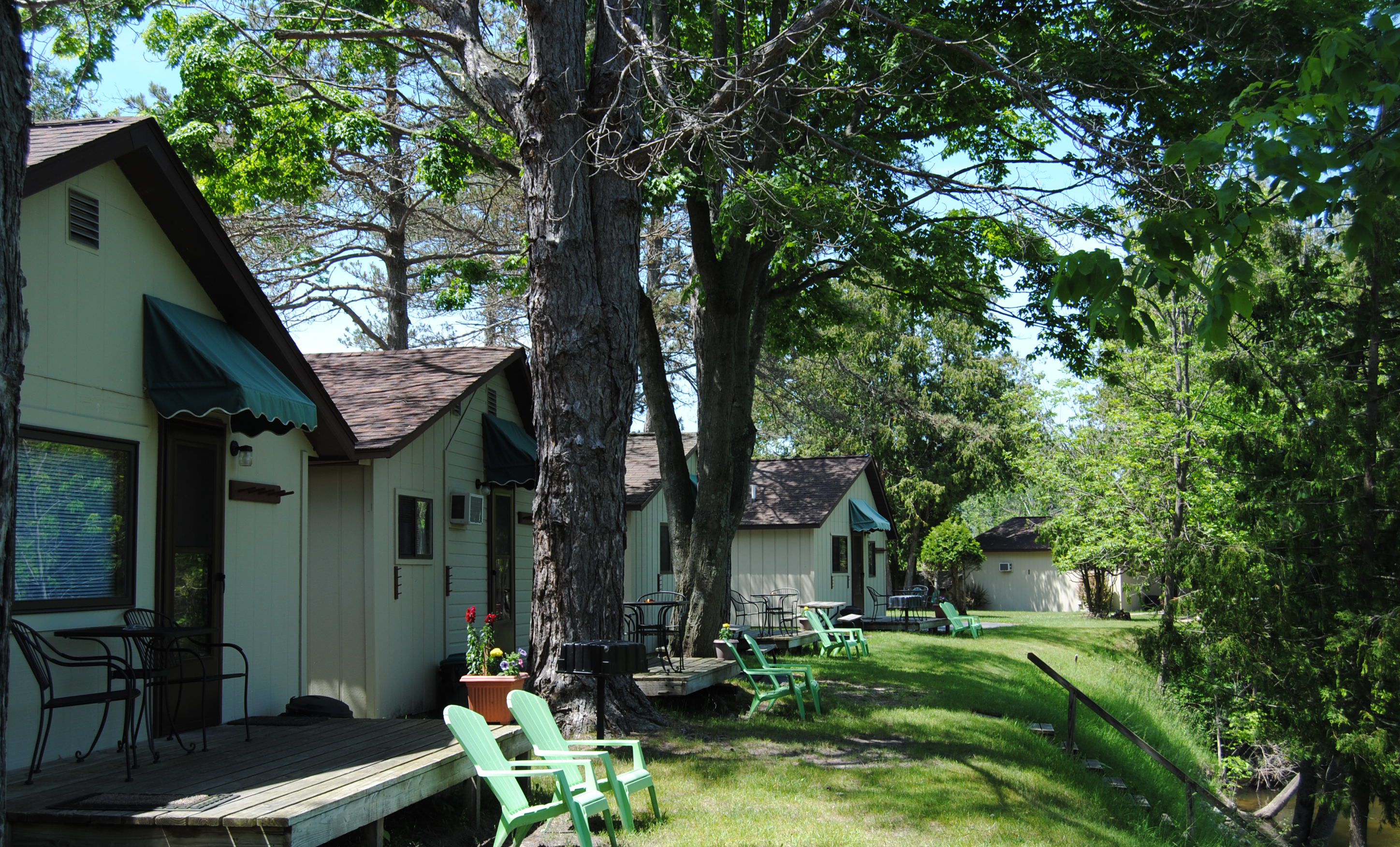 A row of cabins with outdoor seating and a grassy area.