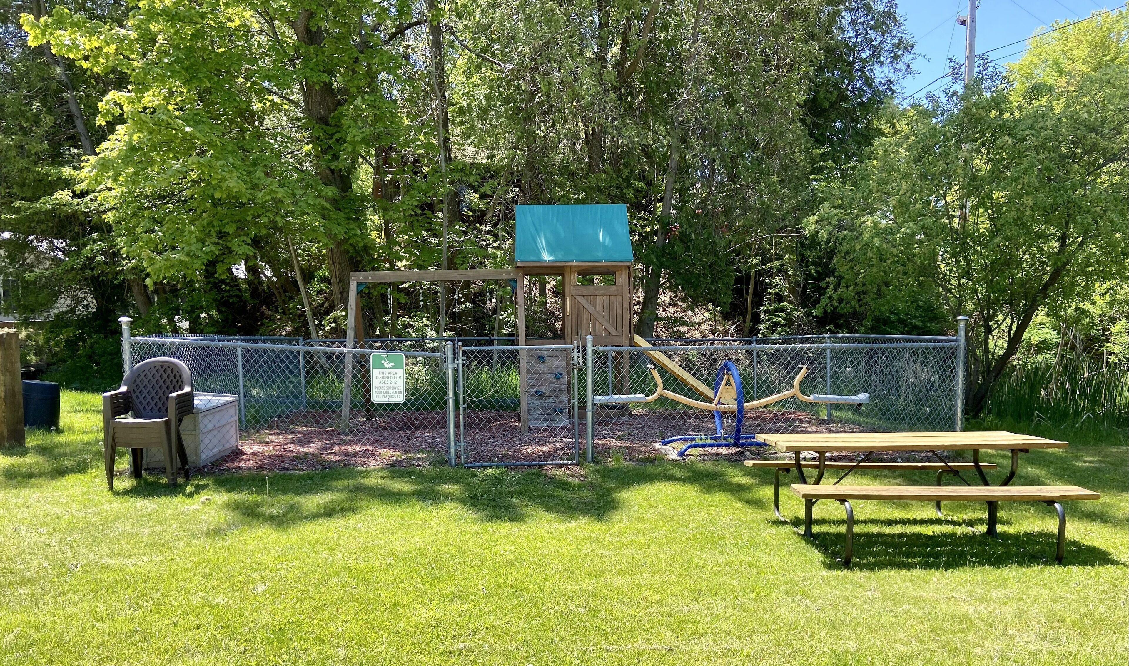 A playground with a slide, swings, and a fenced play area.