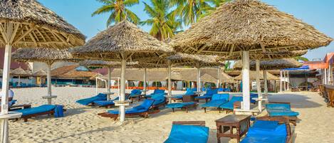 Aan een privéstrand, wit zand, ligstoelen, parasols