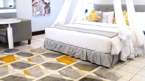 Un dormitorio con cama con dosel, una mesita de noche, una silla, una alfombra y un televisor instalado en la pared.