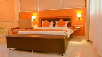 A modern hotel room with a large bed, two bedside tables, a nightstand, and a bathroom with a bathtub.