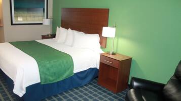 A hotel room with a large bed, a nightstand with a lamp, a wooden headboard, and a green wall.