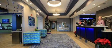 A lobby with a reception desk, seating area, Christmas tree, and a bar.
