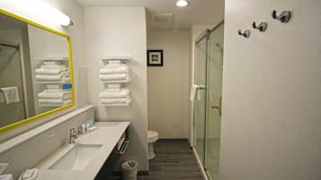 Un baño moderno con un espejo grande, un lavabo, un inodoro y una zona de ducha.