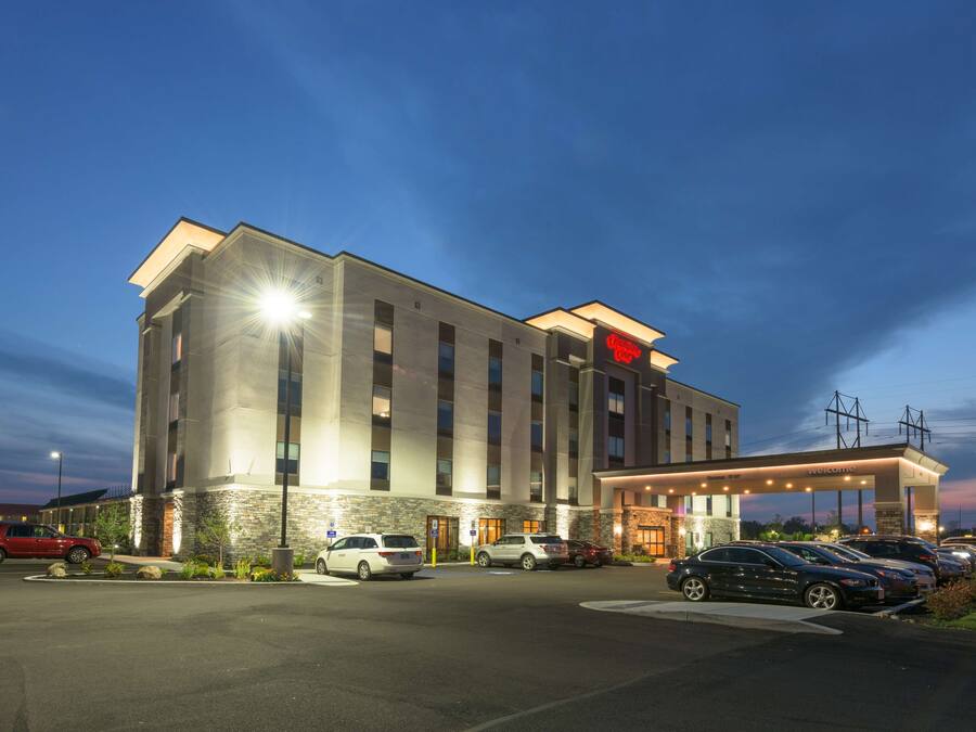 A modern hotel with a prominent 'Chow's Club' sign, a well-lit entrance, and a parking lot with several cars.