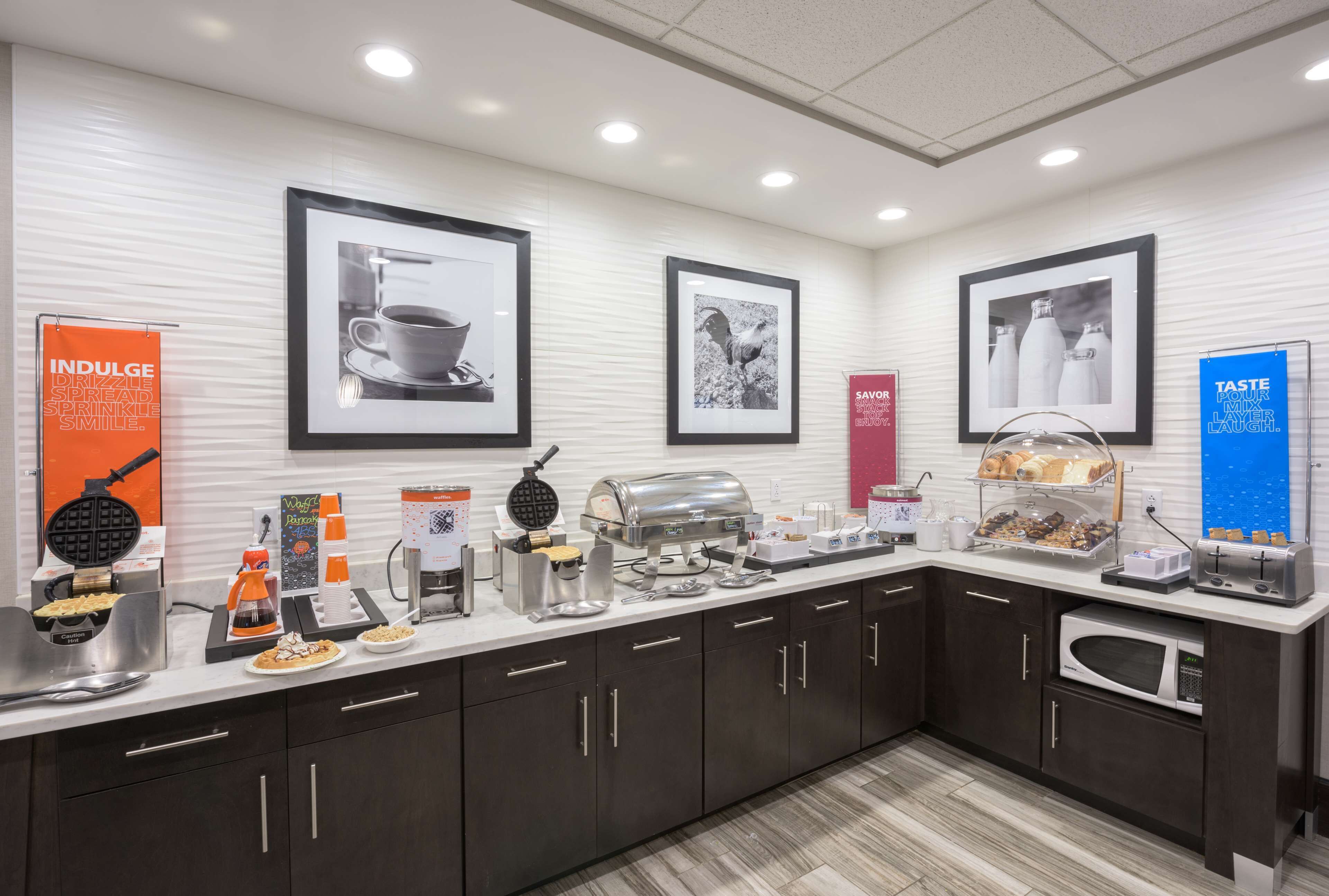 A modern kitchen with a buffet setup, including a waffle maker, coffee station, and various food items.