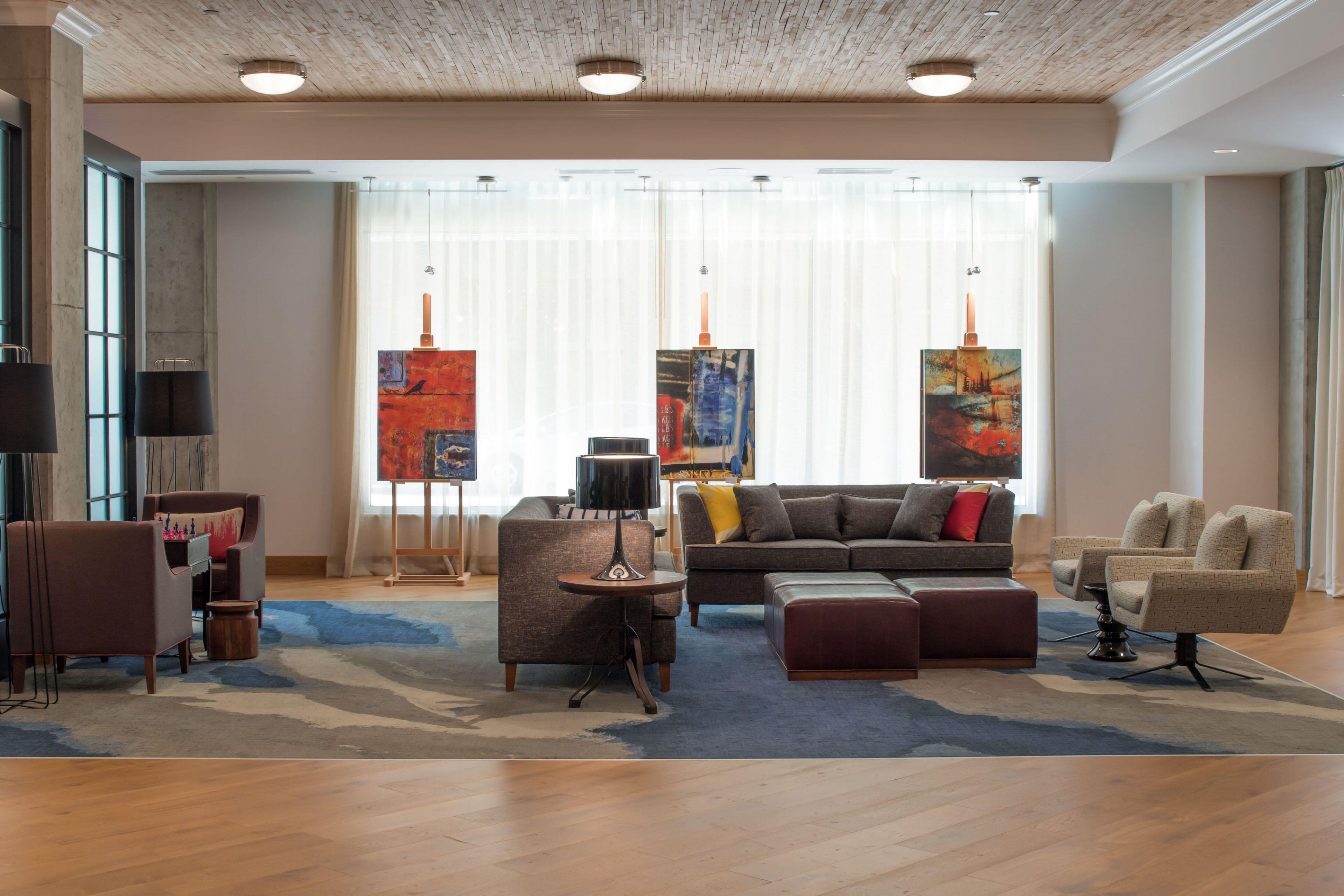 Un salon moderne avec un canapé, des fauteuils, une table basse et des œuvres d’art accrochées aux murs.