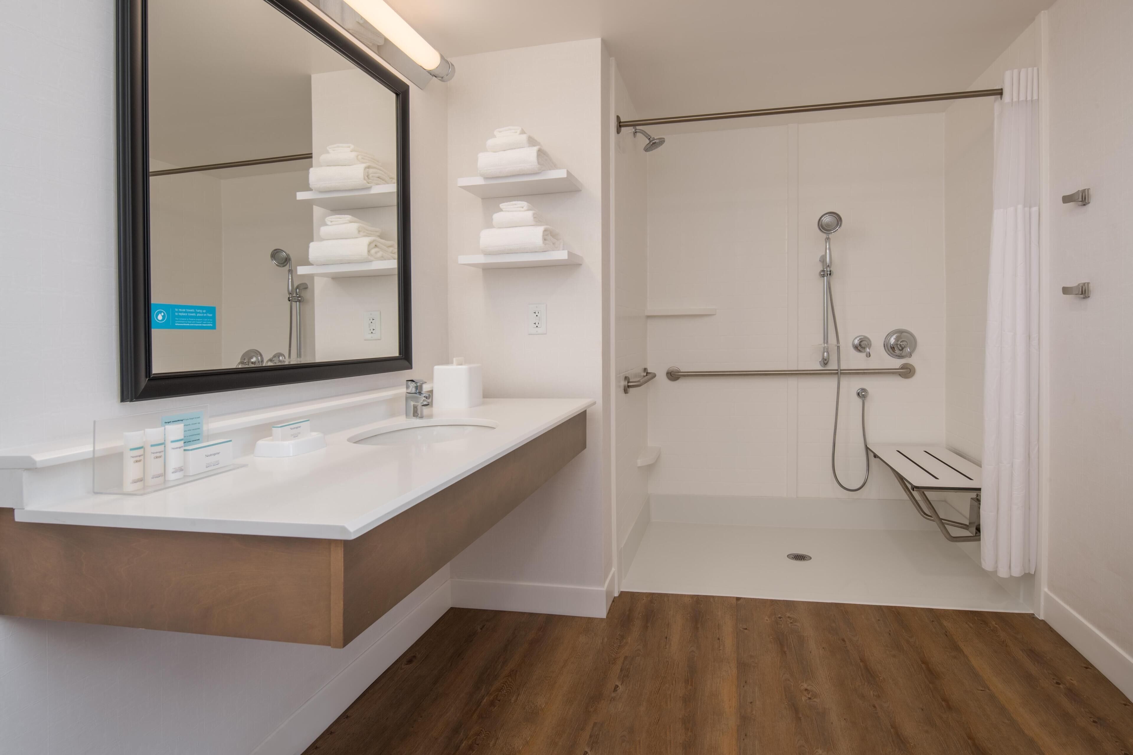 A modern bathroom with a large mirror, white sink, and a walk-in shower.