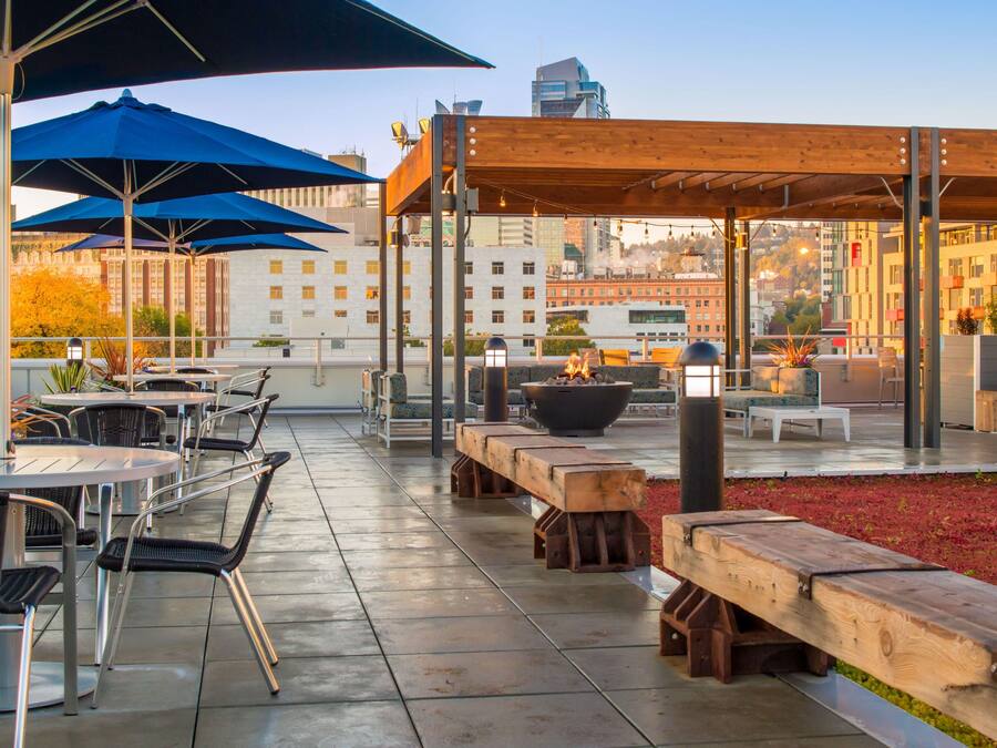 An outdoor patio with tables and chairs, a fire pit, and umbrellas.