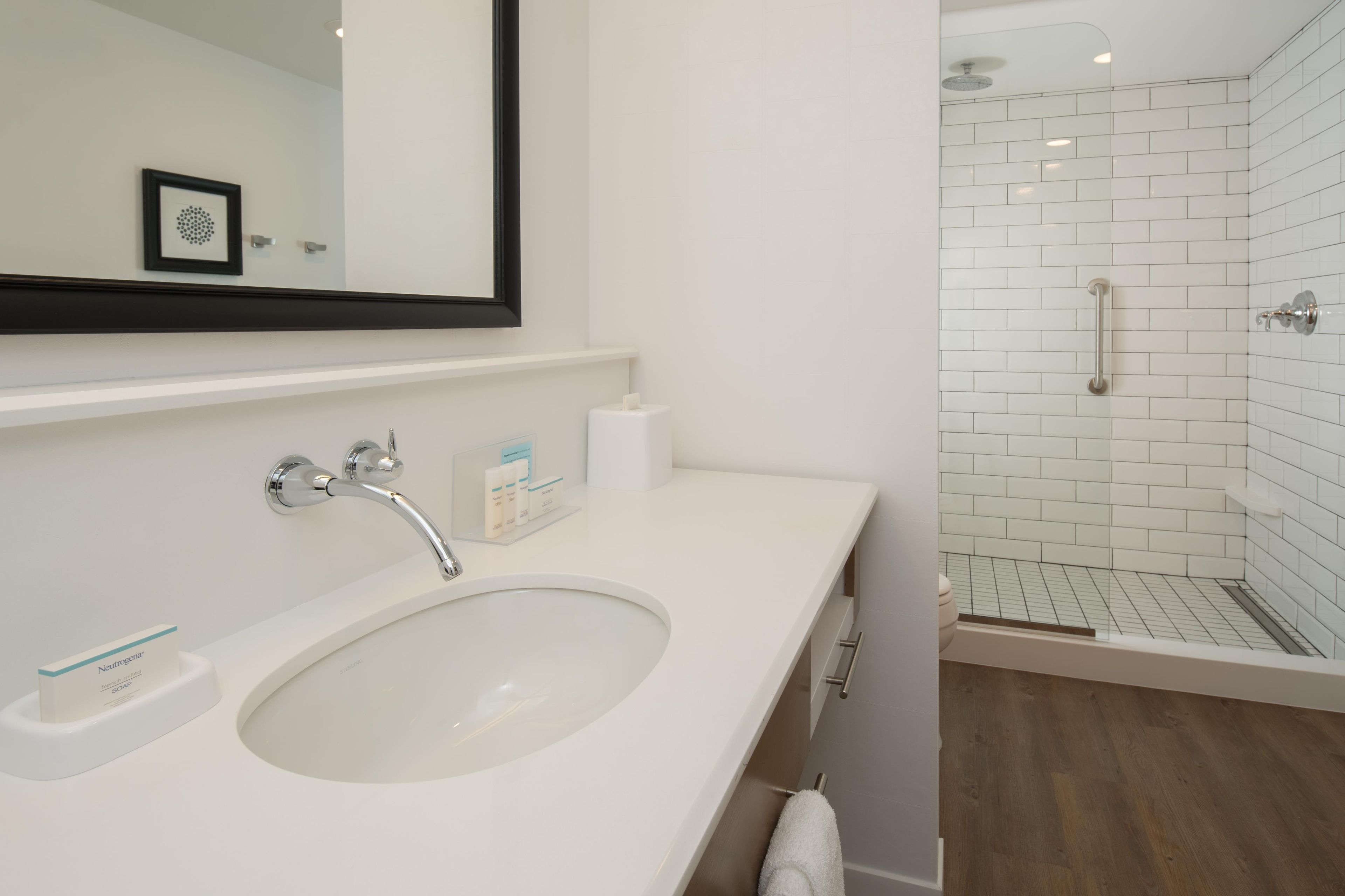 A bathroom with a white sink, a mirror, and a shower with white tiles.