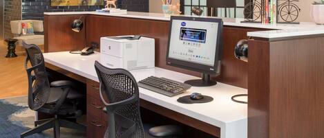 Un bureau moderne, de type « open space », équipé d’un ordinateur de bureau, d’une imprimante et de deux chaises de bureau.