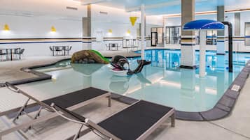 Una piscina interior con sillones de descanso, un trampolín y un puesto de salvavidas.