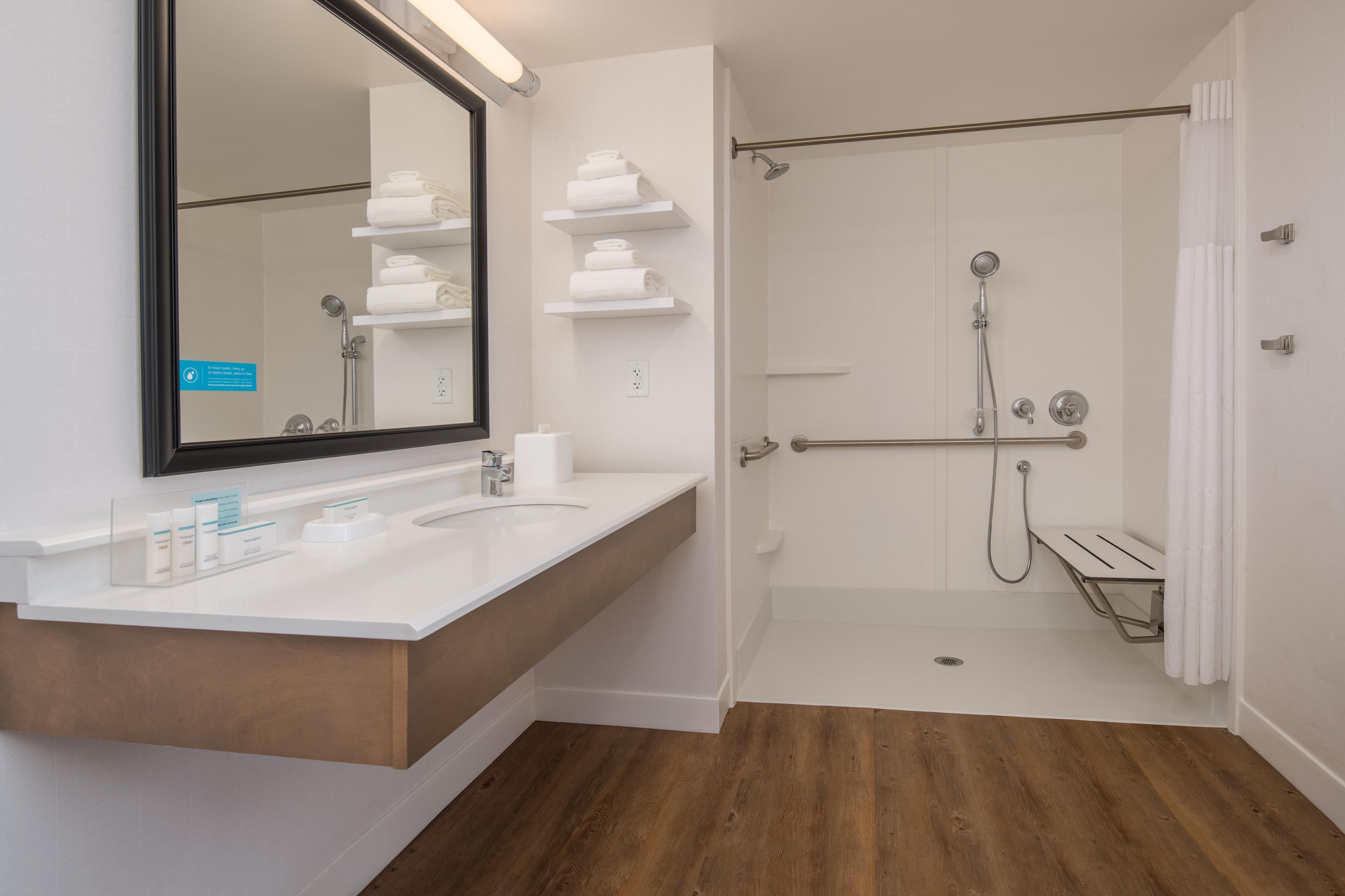 Un bany modern amb un gran mirall, un lavabo amb articles de tocador i una platja de banyera.