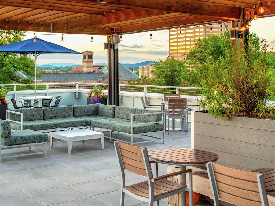 An outdoor patio with a sectional sofa, a round table, and chairs.