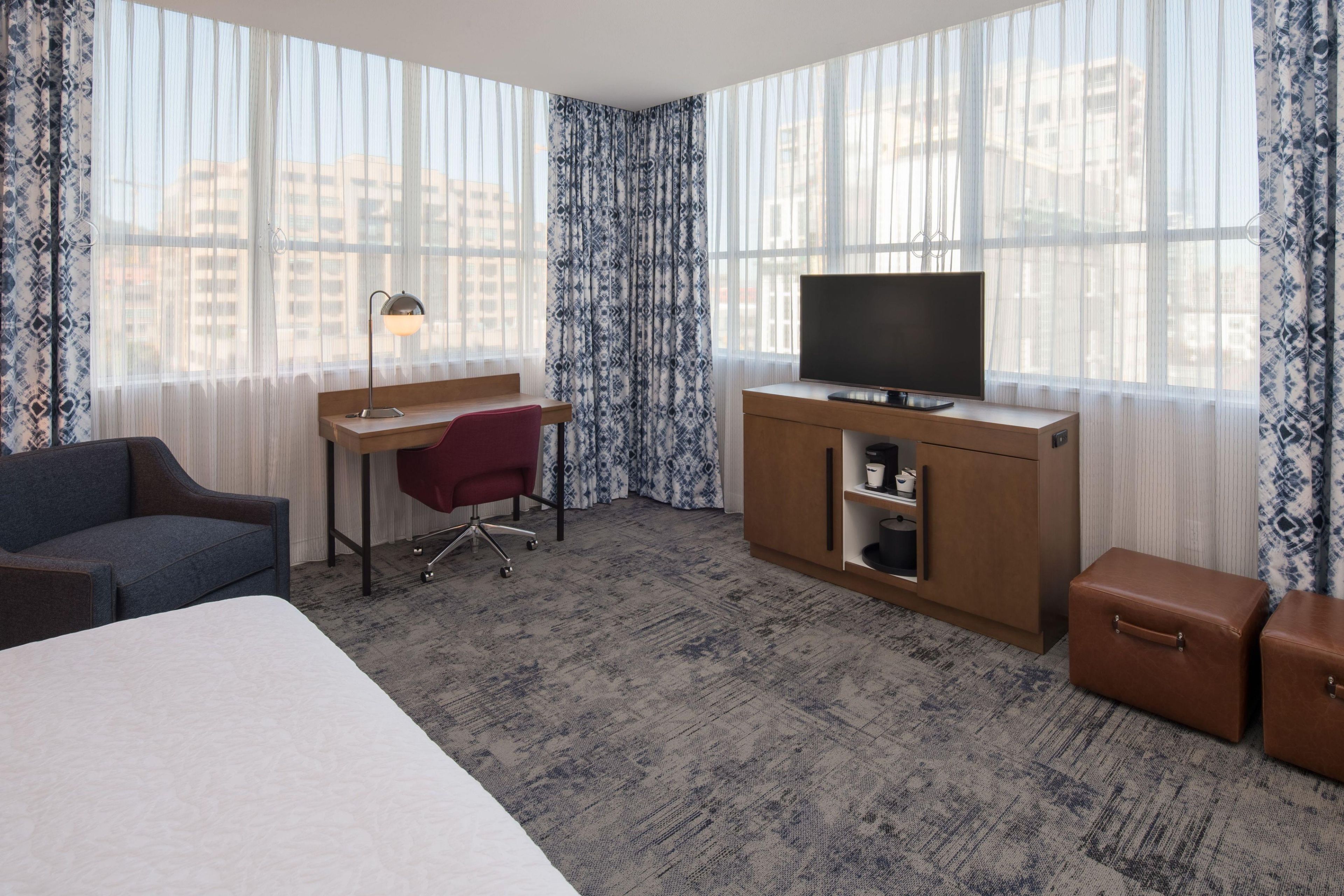 Une chambre d’hôtel comprenant un lit, un bureau avec une chaise, une télévision, une armoire et deux valises.