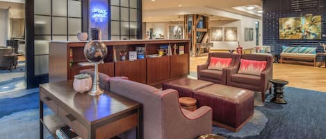 Een moderne hotellobby met een receptiebalie, een zithoek en kunstwerken aan de muren.