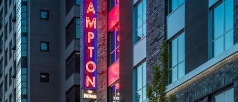 Un hotel con un llamativo letrero de neón que dice "Hampton by Hilton".