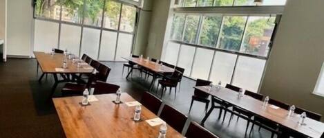 A conference room with long tables, chairs, and large windows.