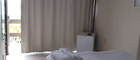 A hotel room with a bed, a ceiling fan, a TV, and a window with curtains.