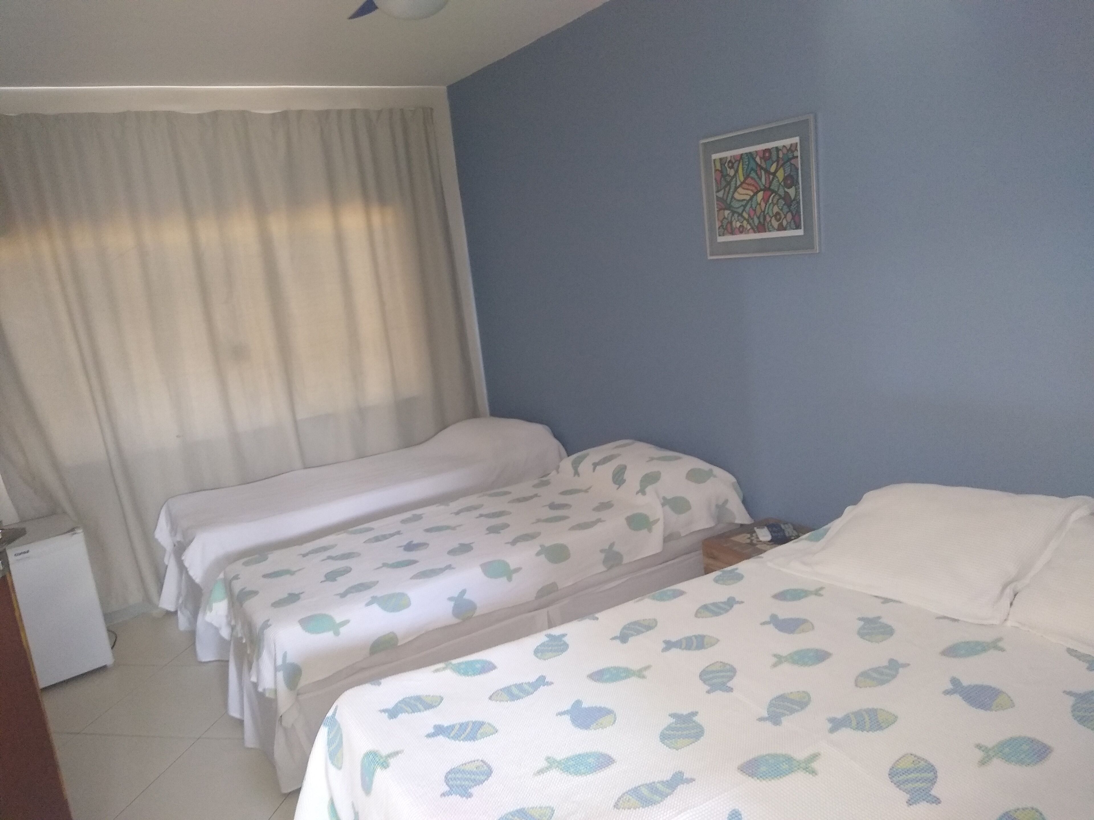A hotel room with two beds, a small desk, and a window with curtains.