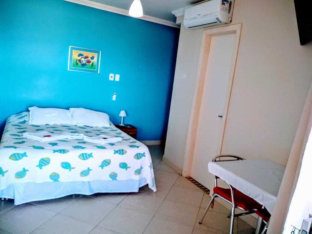A bedroom with a bed, a bedside table, a chair, and a door.