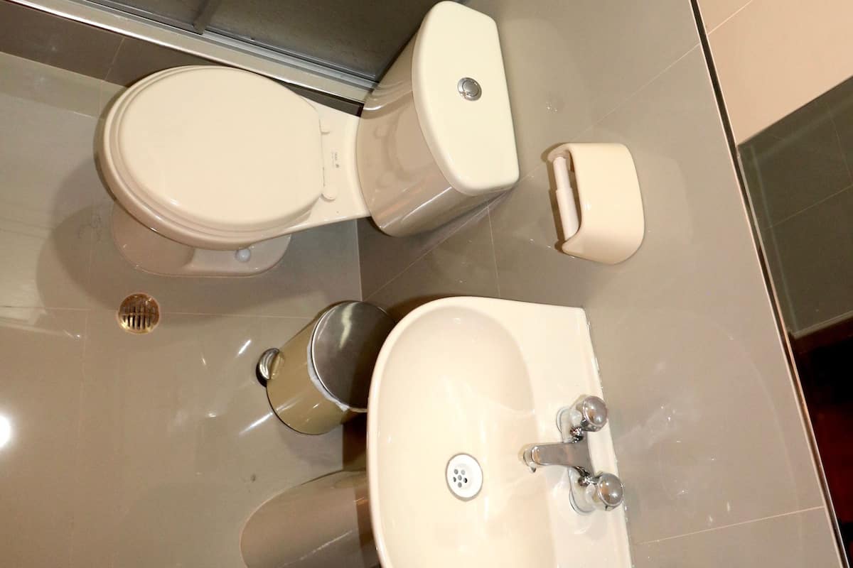 A bathroom with a toilet, sink, and a hand dryer.