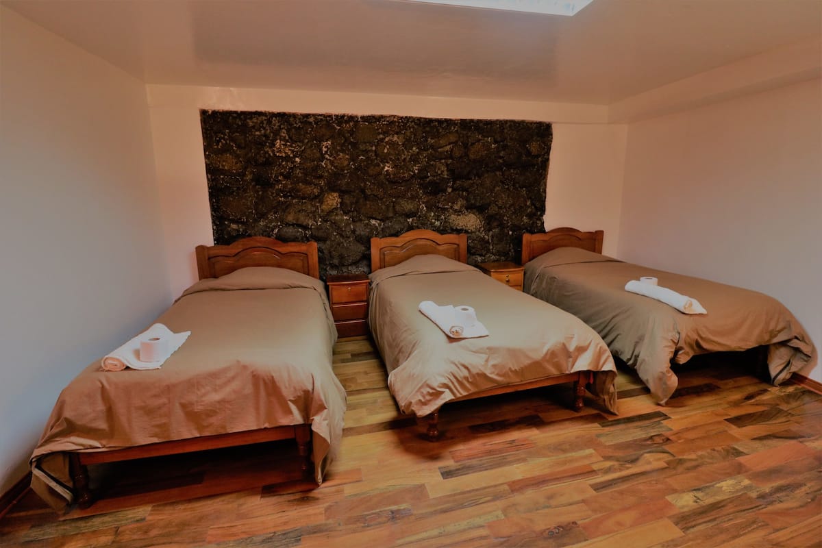 A room with two wooden beds, a stone wall, and a wooden floor.