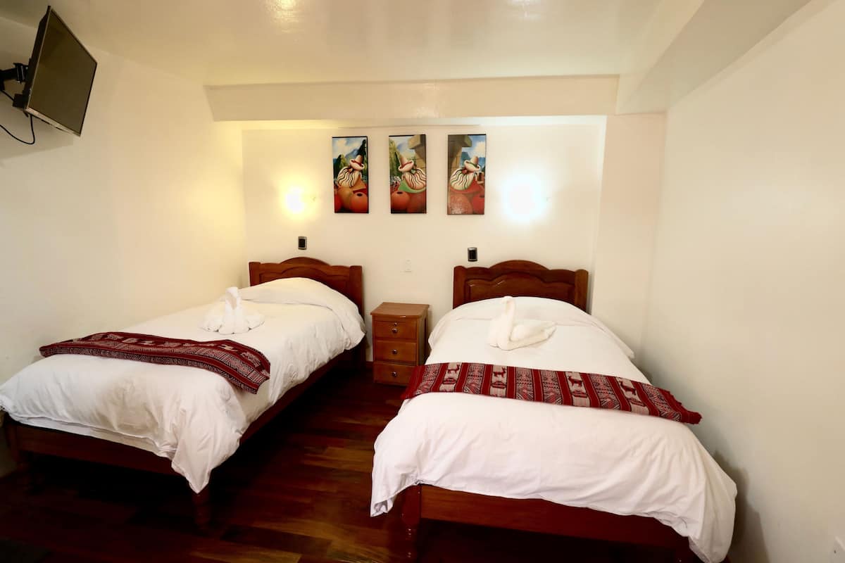 A room with two wooden beds, white bedding, and a small wooden nightstand.