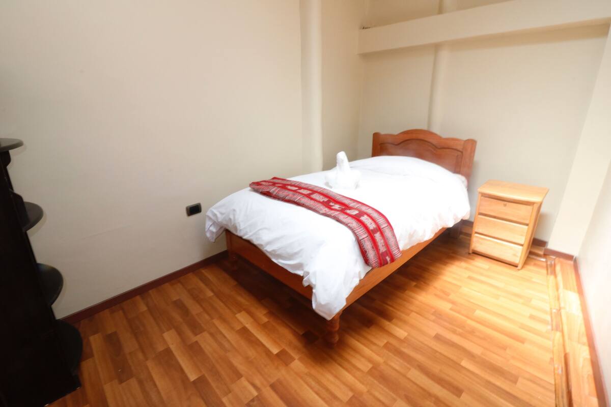A bedroom with a wooden bed, a nightstand, and a dresser.
