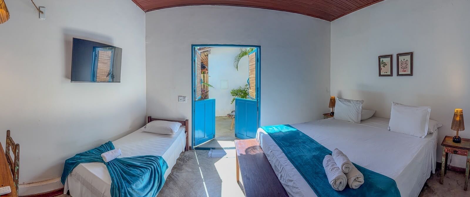 A room with two beds, a door leading outside, and a small table with a lamp.