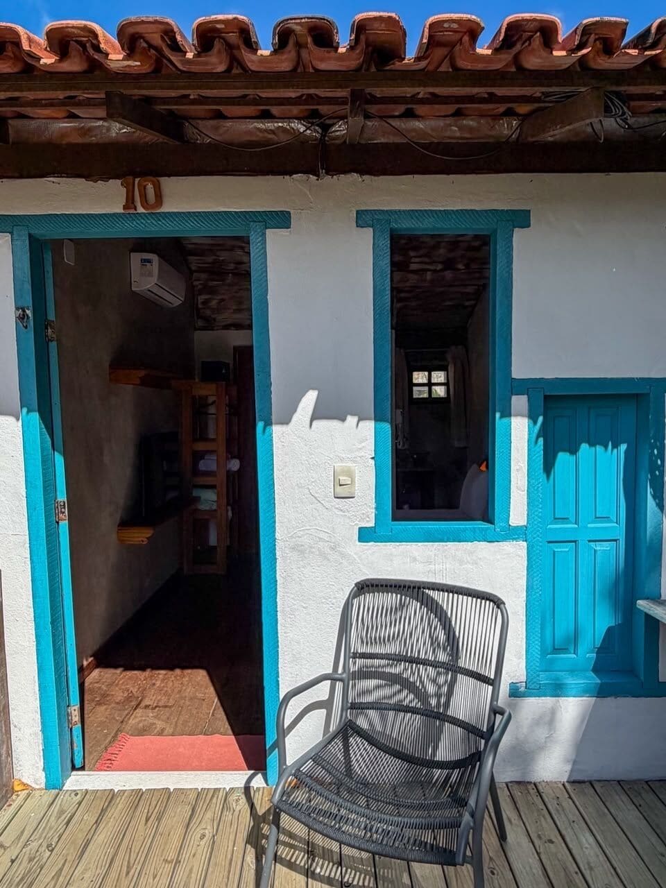 Un edificio con el número '10' sobre la entrada, una puerta azul y una silla afuera.