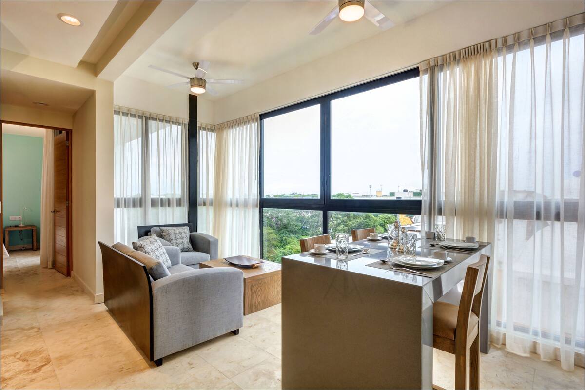 Een moderne woonkamer met een bank, eettafel en grote ramen.