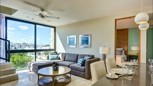 A modern living room with a sofa, coffee table, and dining area set up for a meal. - Anah Suites - Las Flores Properties (Playa del Carmen)