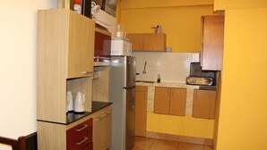 A compact kitchen with wooden cabinets, a stainless steel refrigerator, a coffee maker, and a microwave. - Qori punku - Hostel (Cusco)