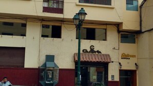 A multi-story building with a ground-floor restaurant and a visible telephone booth. - Qori punku - Hostel (Cusco)