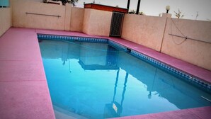A rectangular swimming pool with a tiled edge and a pink deck.