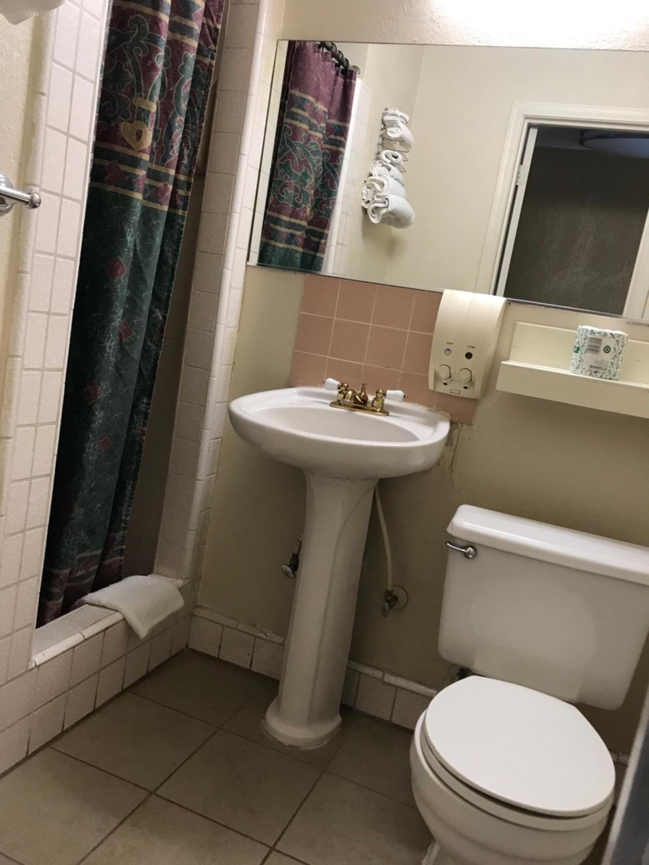 A bathroom with a pedestal sink, toilet, and a shower curtain.
