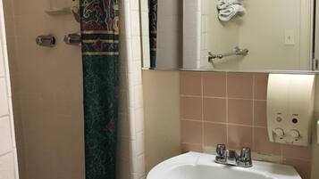A bathroom with a shower, a sink, a mirror, and a towel rack.