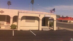 A small building with an American flag, a sign indicating an office vacancy, and a parking lot.