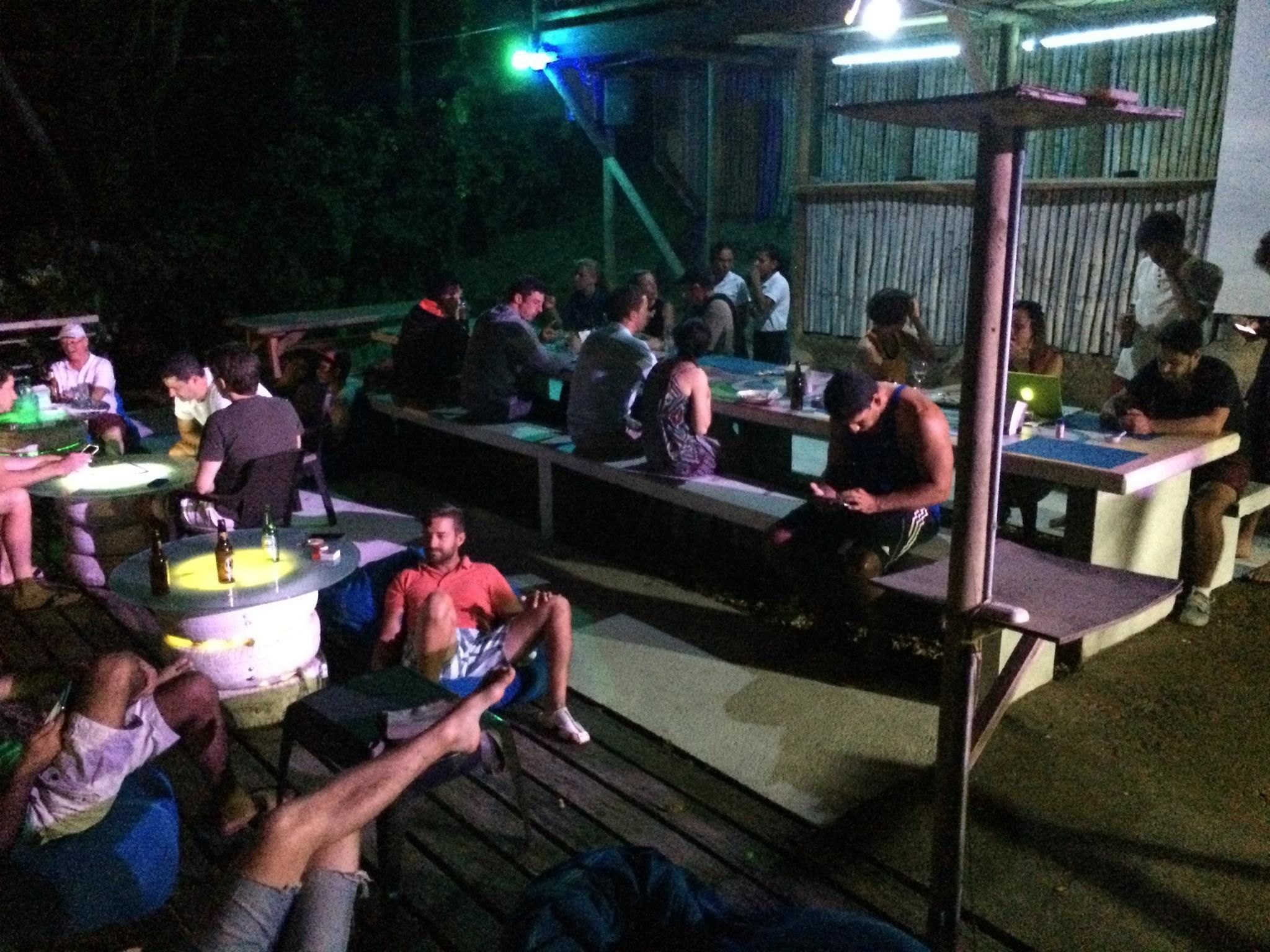 An outdoor dining area with multiple tables and benches, surrounded by a wooden deck.