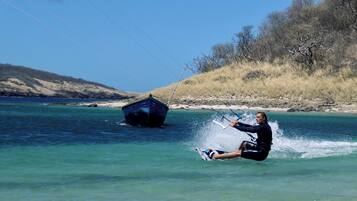 A person water skiing on a clear blue lake with a boat in the background.