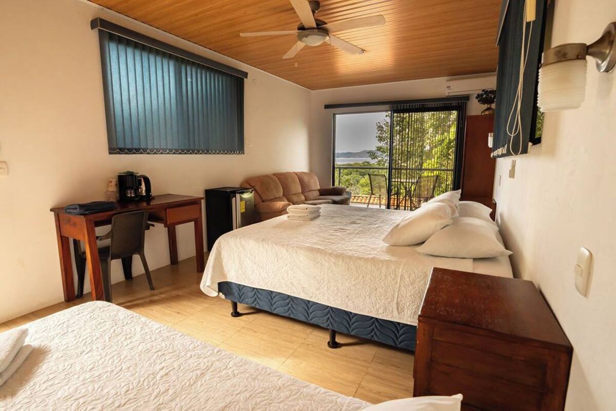 Une chambre à coucher comprenant un lit, un bureau, une chaise et donnant sur l’extérieur.