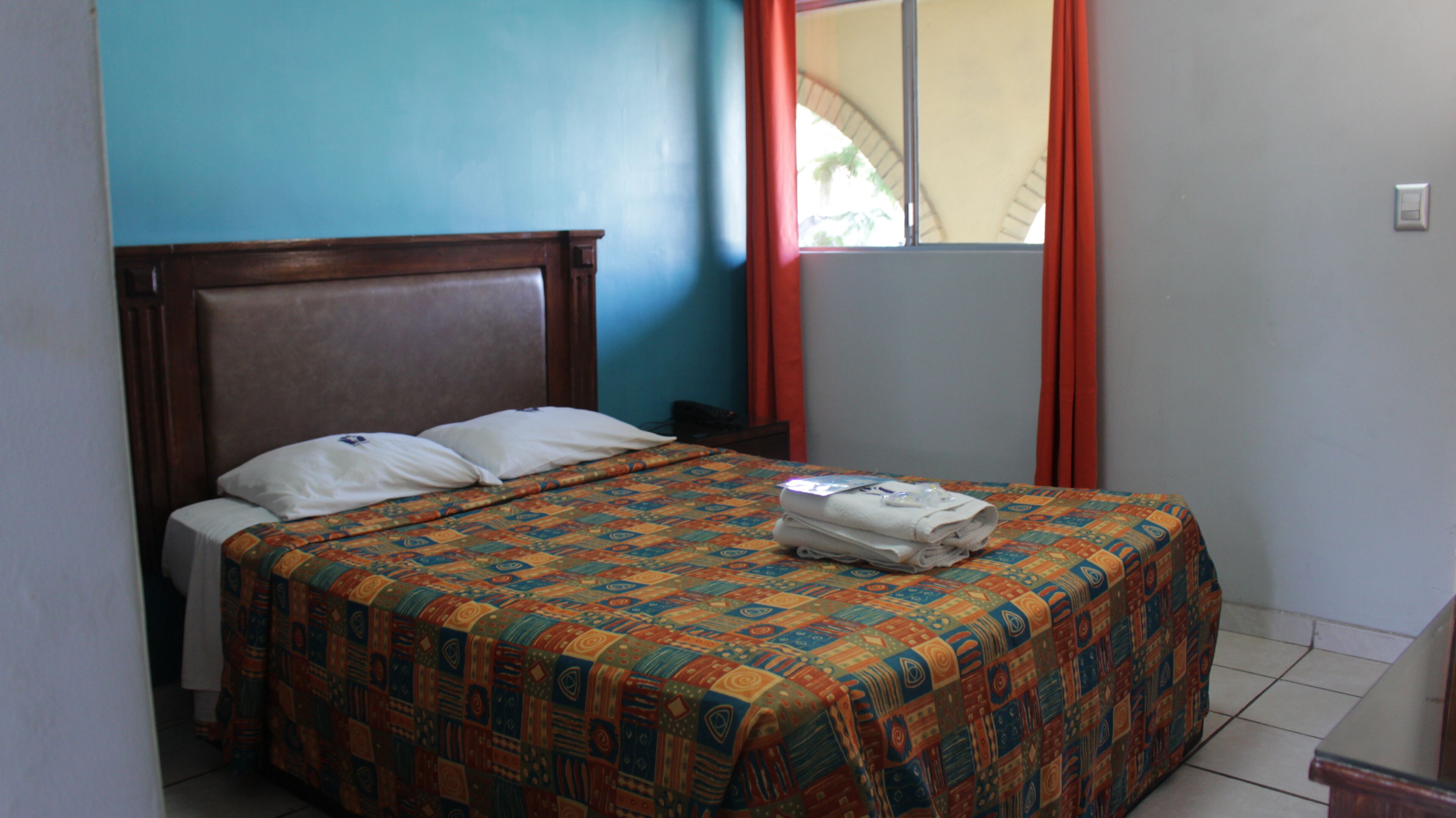 A bed with a patterned bedspread, a wooden headboard, and two pillows.