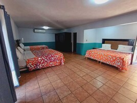 Habitación de hotel con dos camas, cada una con colcha estampada, ventilador de techo y aire acondicionado.