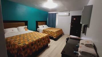 Habitación de hotel con dos camas, un escritorio con silla, televisión y aire acondicionado.