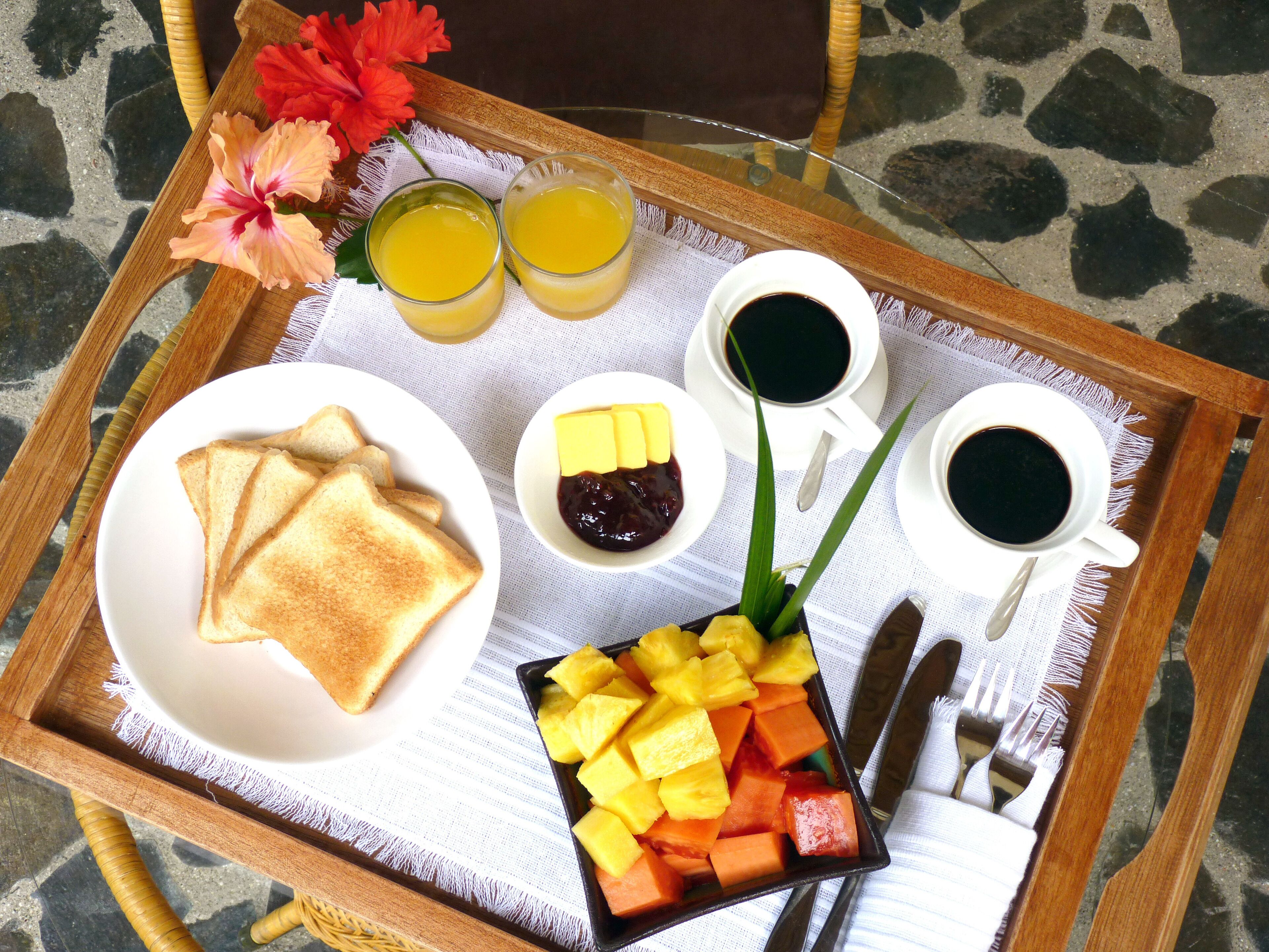 A tray with toast, fruit, juice, and coffee.